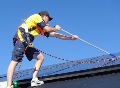 Technicus met veiligheidsuitrusting voor het reinigen van zonnepanelen